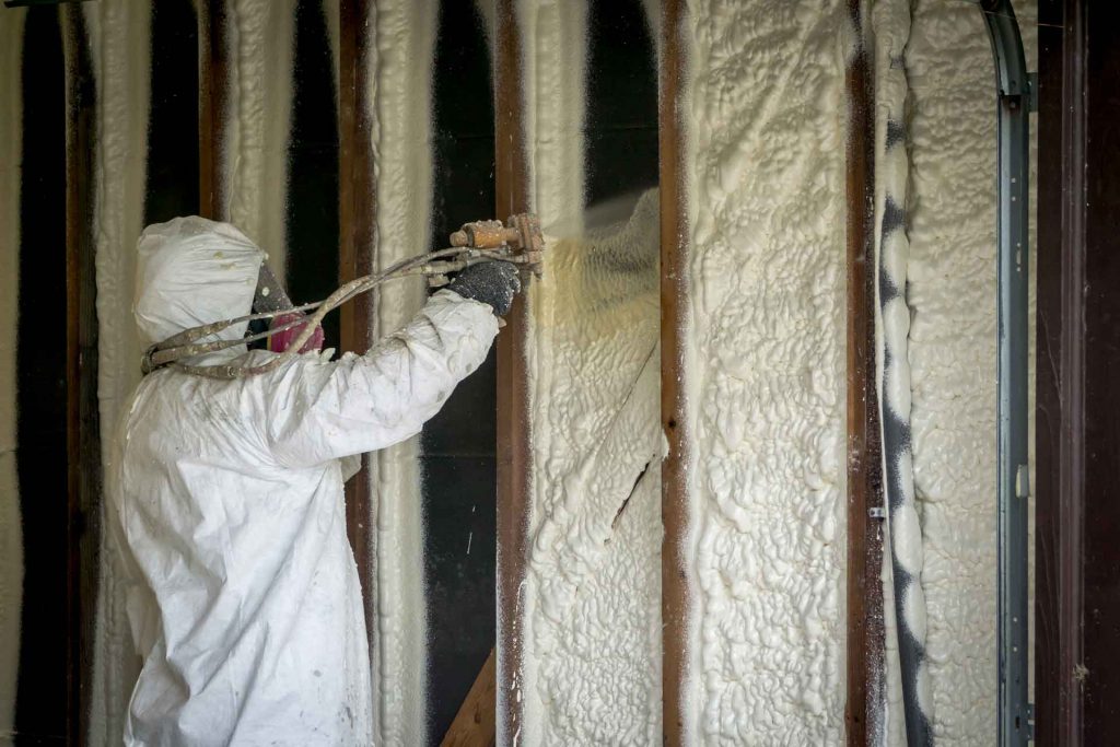 A man spraying in spray foam insulation