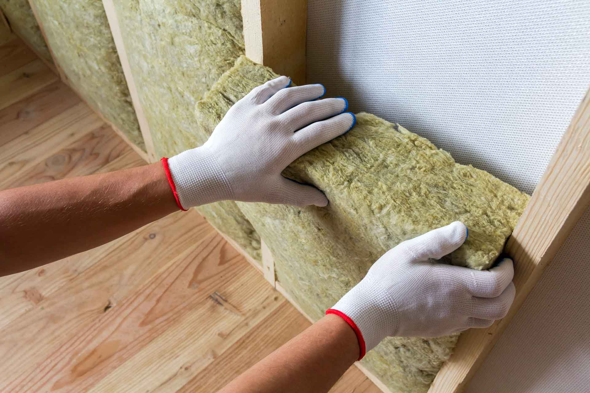 Two gloved hands removing a panel of rock wool insulation